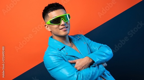 Stylish young Asian man in blue leather jacket and green sunglasses