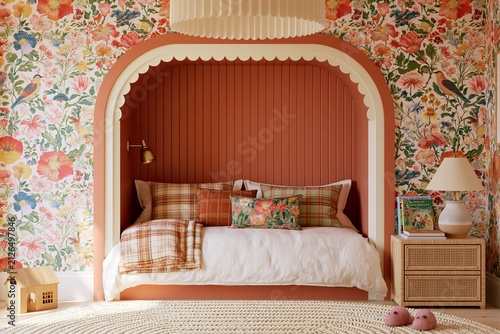 Whimsical girls bedroom featuring a built-in bed nook with floral wallpaper, cozy bedding, and decorative elements in a bright and inviting interior space