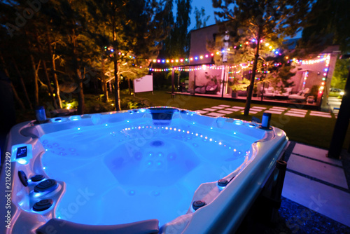 Quadro su tela Warm water jacuzzi sits in a backyard under colorful lights during a summer even
