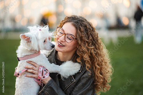 Konstfotografi Young woman smiling while bonding with her cute pet dog