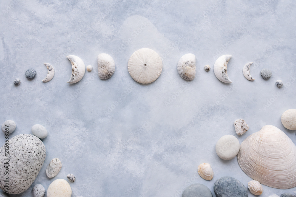 Obraz premium Various seashells and small stones are arranged on a light blue, textured surface.