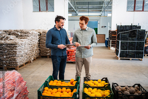 Two men discussing inventory in a fresh produce warehouse