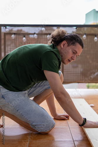 Man positions wooden boards on a floor before furniture assembly in a home workshop. DIY preparation and precision support efficient woodworking and home renovation