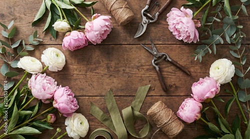 Flat lay of fresh botanical flowers, gardening shears, and twine on a wooden table