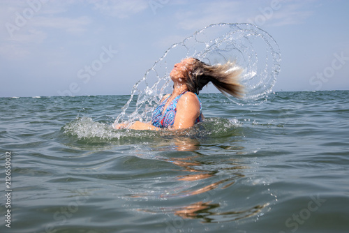 Foto Donna sorridente che lancia indietro i capelli bagnati creando uno spettacolare