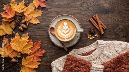 Autumn flat lay with latte art, maple leaves and cozy sweater