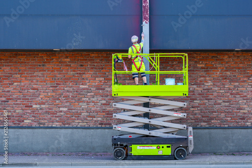 Construction Worker Painting Steel Support Column from Scissor Lift at Commercial Building Exterior Site