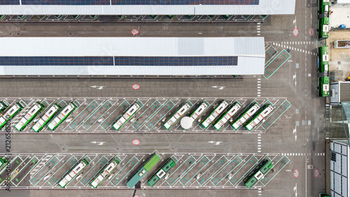 Aerial view of a modern electric bus depot with rows of green buses parked in an organized urban transport facility, San Donato Milanese, Lombardy, Italy.