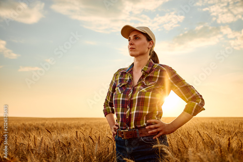 Cuadro en lienzo Female farmer standing proudly in a golden wheat field at sunset, looking forwar