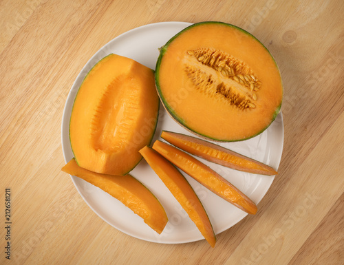 Фотография Fresh cantaloupe fruit cut on a white plate