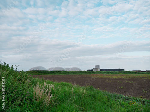 Fotografía The domes of a rural biogas installation on the horizon beyond a ploughed field