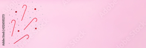 Pink holiday background with candy canes, red and silver stars on left side, leaving wide copy space for festive banners, sales, greetings and seasonal promo designs.