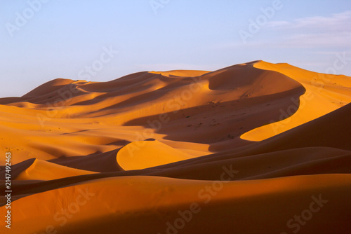 Sand dunes with lines and shadow in Sahara Desert under blue sunny sky