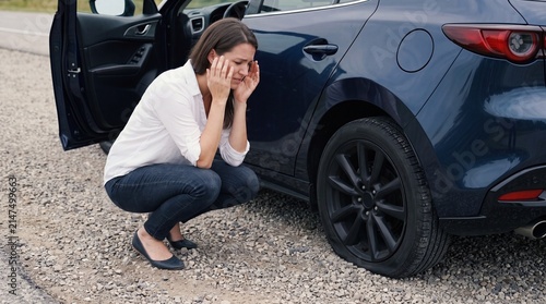 Frustrated Woman Looking at Flat Tire on Roadside Concept of Unexpected Vehicle Breakdowns and Travel Woes