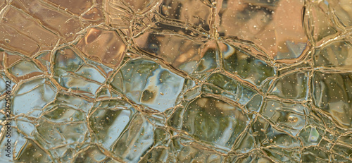 Abstract textured glass surface with muted blue, brown and beige tones, organic lines and distorted reflections.