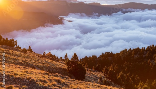 Golden sunrise over misty autumn forest mountains.