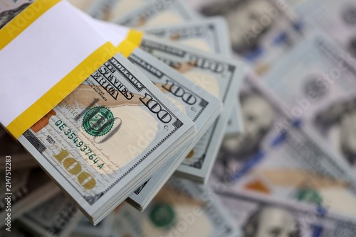 Ten thousand dollars packs lies in stack on big amount of hundred dollar bills banknotes close up