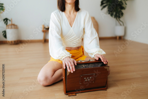Quadro su tela Woman seated with a harmonium in a bright home, soft photographic style, wooden