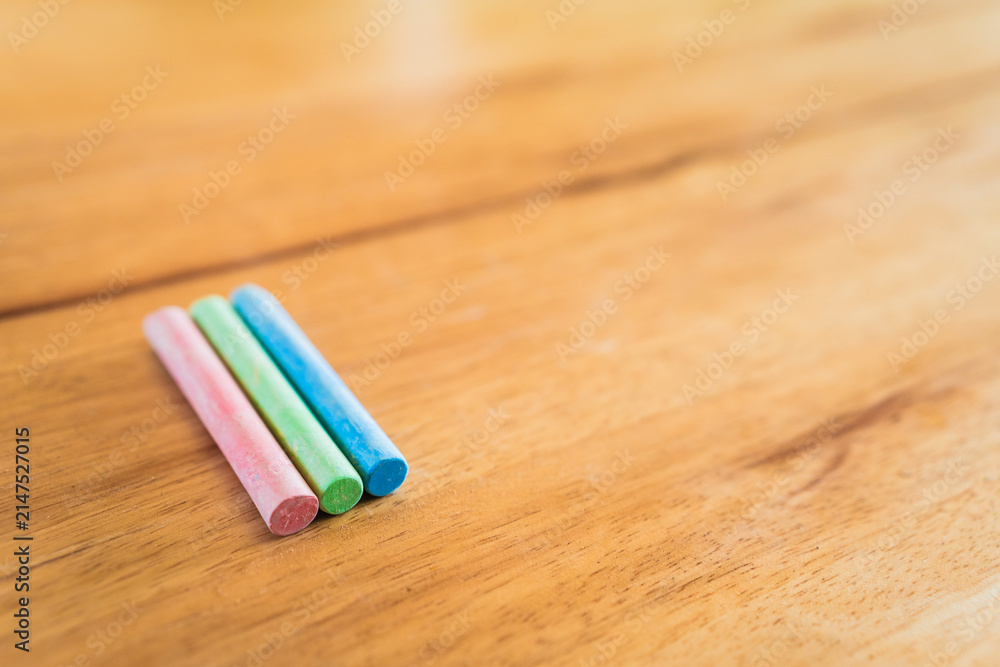 Fototapeta premium Creative educational design concept: colored pencils and chalk for back to school with a wooden table background