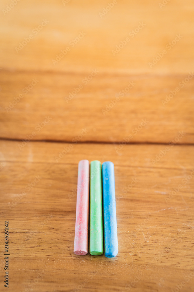 Fototapeta premium Creative educational design concept: colored pencils and chalk for back to school with a wooden table background