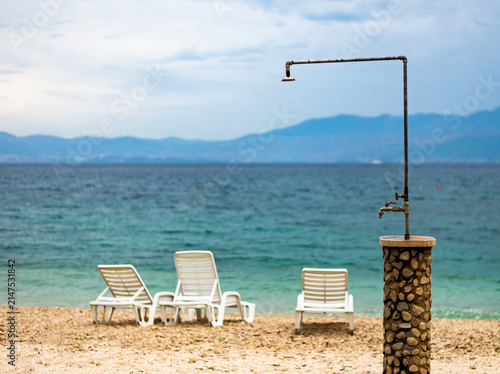 Foto Beach view with shower and lounge chairs near the water in a coastal area during