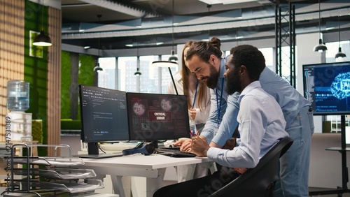 фотографія Programmer requests help from coworkers after a critical error warning appears, and the office team brainstorms how to fix a computer bug affecting software systems and applications