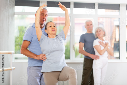 Konstfotografi Diligent mature woman practicing ballet positions in pair with man in dancehall