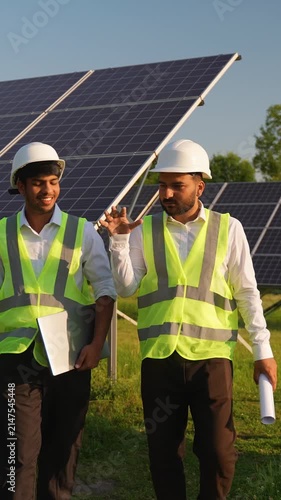 Two solar farm engineers discussing project and walking