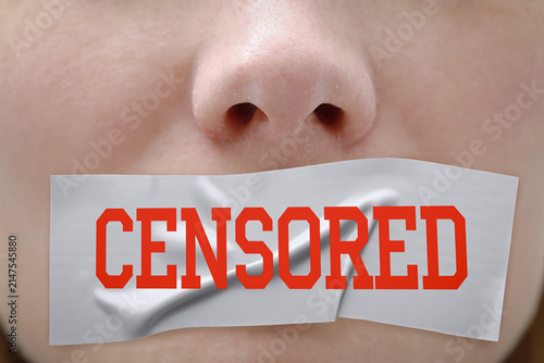 Woman's mouth taped shut with piece of paper marked Censored, closeup. Censorship concept