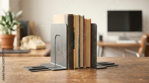 Rustic metal bookends holding a stack of vintage hardcover books