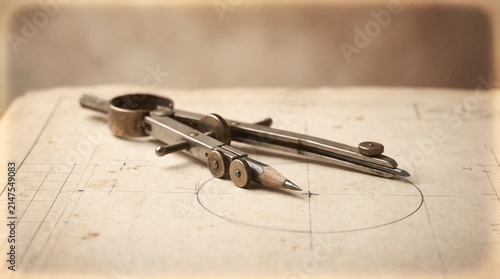 Vintage metal drafting compass drawing a circle on technical paper