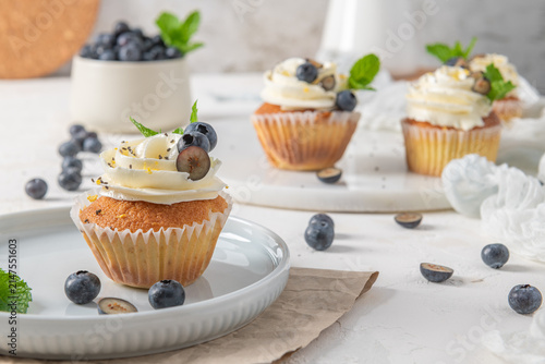 Принти на полотні Delicious vanilla cupcakes with white frosting fresh blueberries and mint