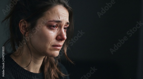 profile view of a crying woman showing deep sorrow and heartbreak in dark room