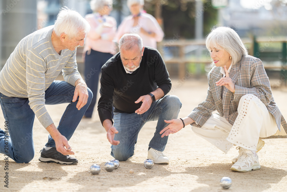 Fototapeta premium Attentive retired seniors discussing the competition while enjoying petanca on a sunny day
