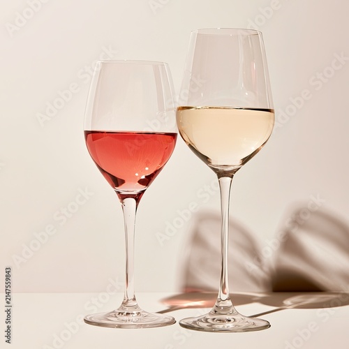Rose and white wine sit in glasses against a clear background.