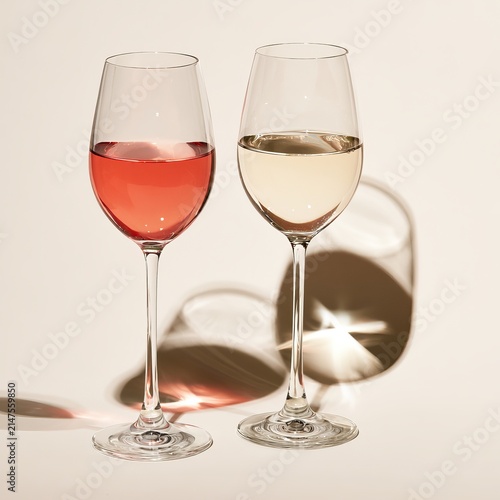 Rose and white wine sit in glasses against a clear background.