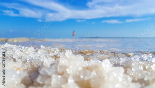 Salt crystals on the Dead Sea shore under a bright blue sky.