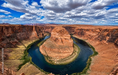 Panoramic view of Horseshoe Bend where the Colorado River curves dramatically through towering red sandstone cliffs near Marble Canyon, Arizona. The iconic landscape, located within Glen Canyon Nation