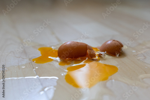 Close-up of broken raw egg splattered on wooden parquet floor