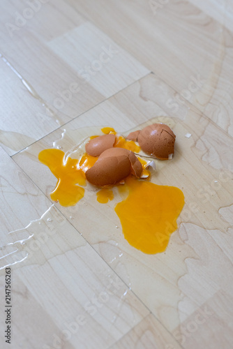 Close-up of broken raw egg splattered on wooden parquet floor