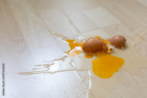 Close-up of broken raw egg splattered on wooden parquet floor