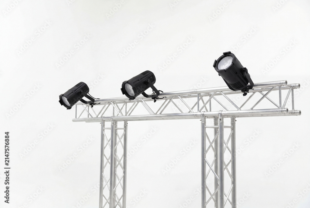 Obraz premium Three black stage lights mounted on silver truss over white background