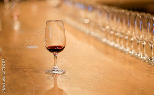 Glass of red wine placed on wooden table with out-of-focus empty wine glasses backdrop
