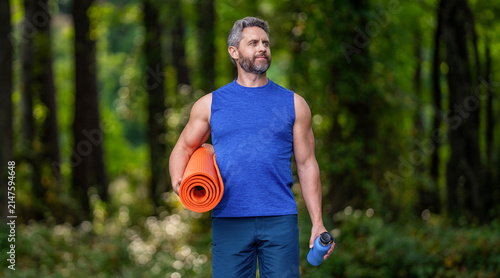 Fotografie Man in sportswear with fitness mat outdoor