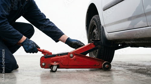 Mechanic Using Red Hydraulic Floor Jack to Lift Car for Maintenance and Tire Change