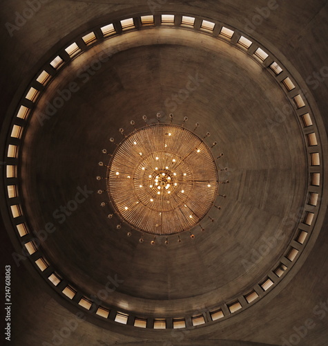Bottom-up view of a large luxurious crystal chandelier with glowing warm lights.