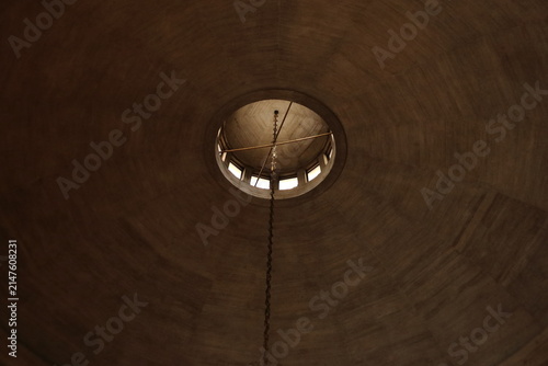 Low-angle view of a wooden dome ceiling with a central oculus skylight and hanging chain