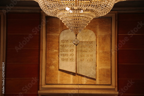 Luxurious crystal chandelier hanging in front of Hebrew Ten Commandments tablets in a synagogue