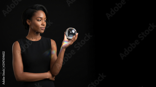 Young African American woman holding crystal sphere with rainbow light