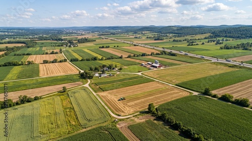 Aerial View of Agricultural Fields: An expansive vista showcases meticulously cultivated agricultural fields, with alternating crops forming a vibrant patchwork of greens and golds under a clear sky.